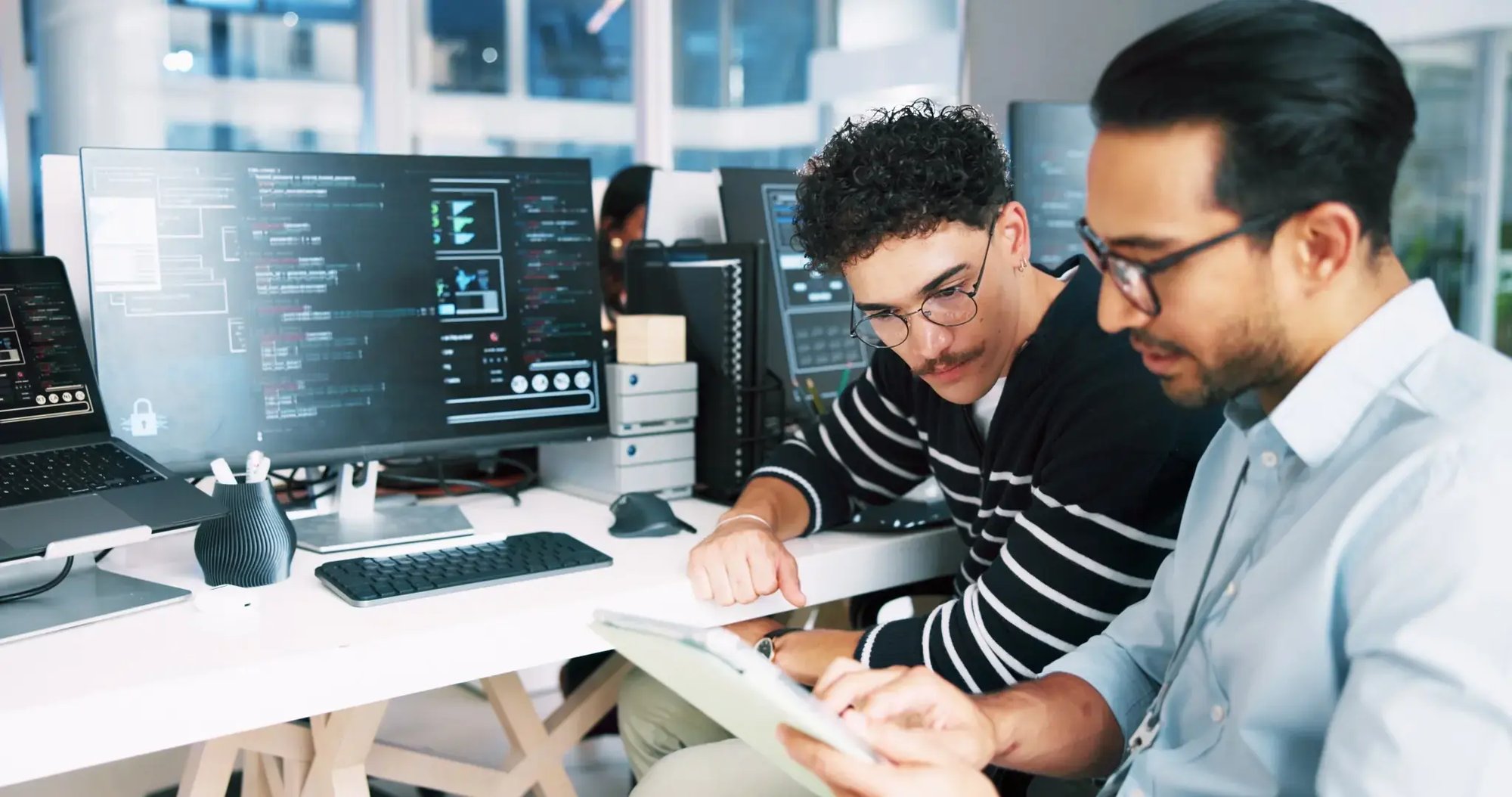 Two developers reviewing code on a tablet in an office Two developers reviewing code on a tablet in an office