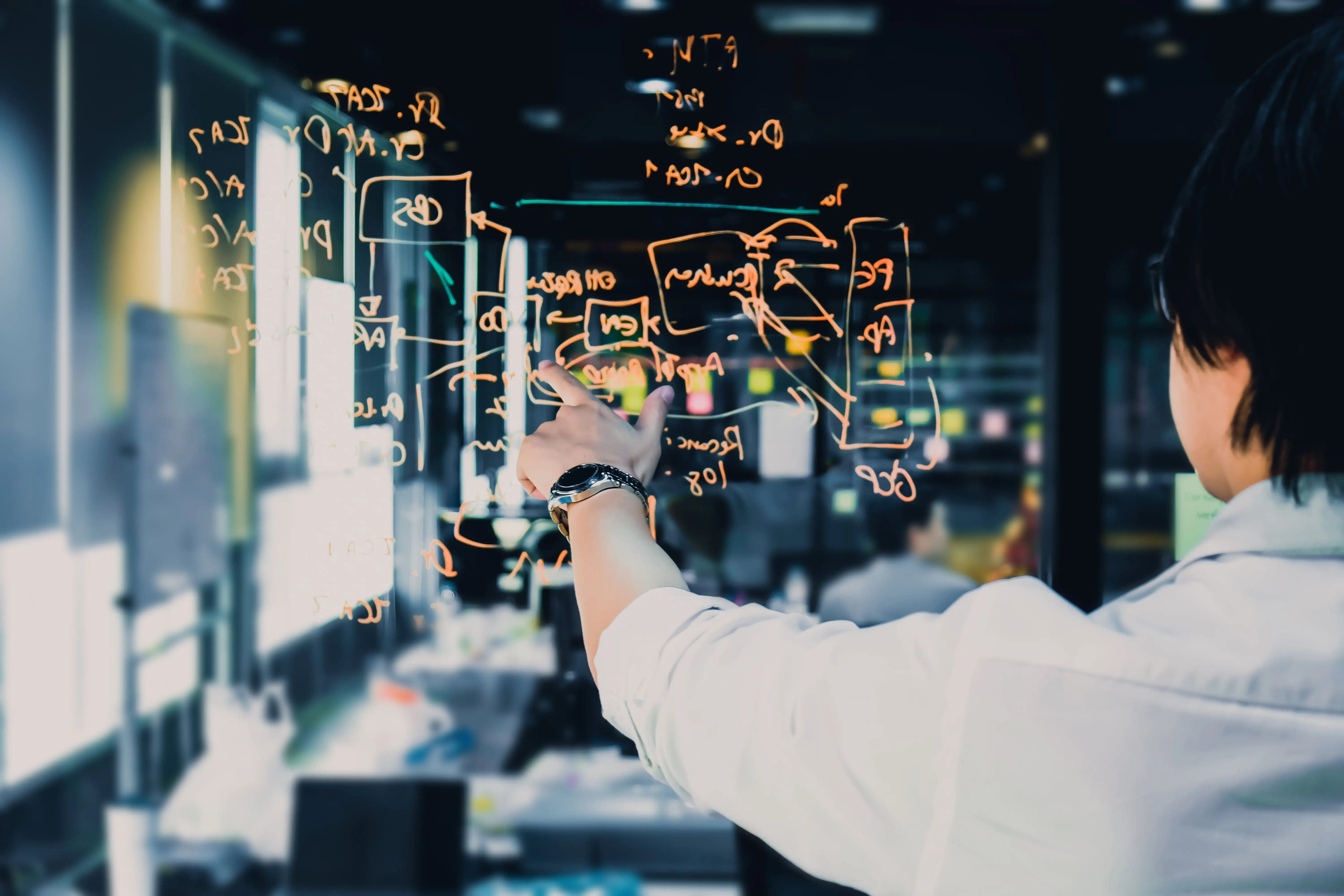 Man writing calculations on a glass pane in an office
