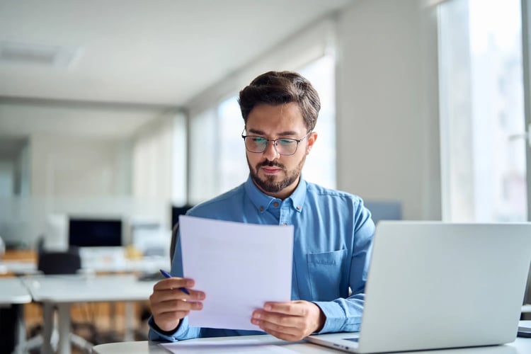 Young busy latin professional business man checking document working at laptop computer in office
