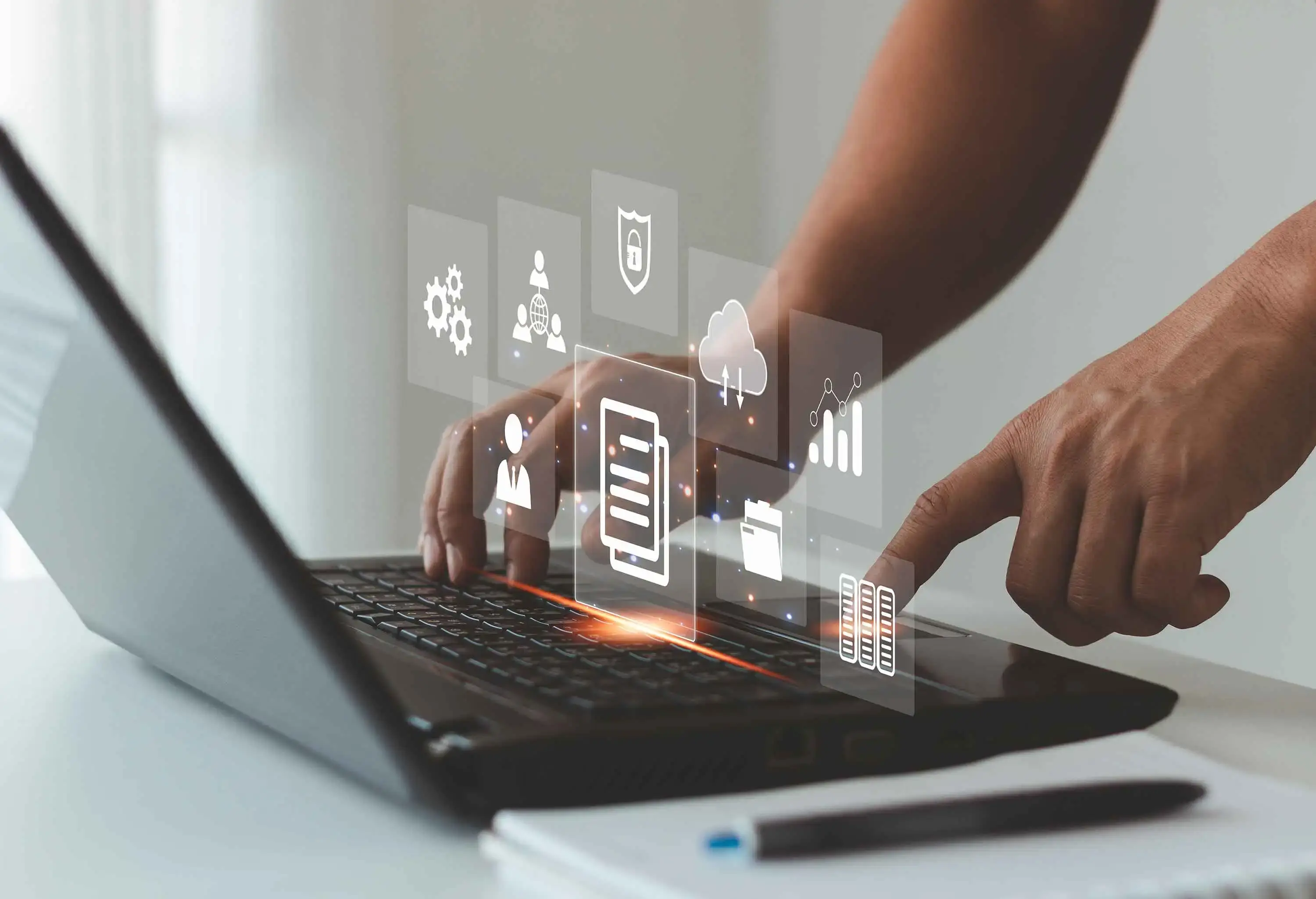 A person working on a laptop with various icons displayed on the screen