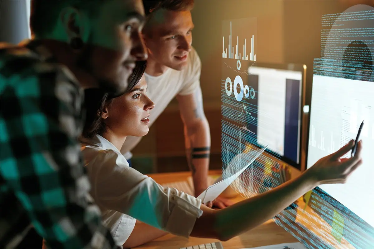 Three people looking at a screen overlay of statistics