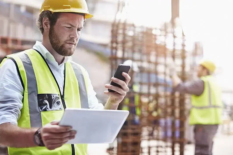 construction worker using a mobile app made by Bertoni Solutions to compile  reports on-site