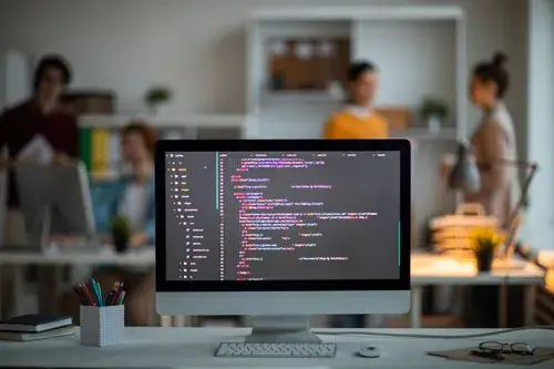 A computer screen displaying code on a desk, representing IT staff augmentation services